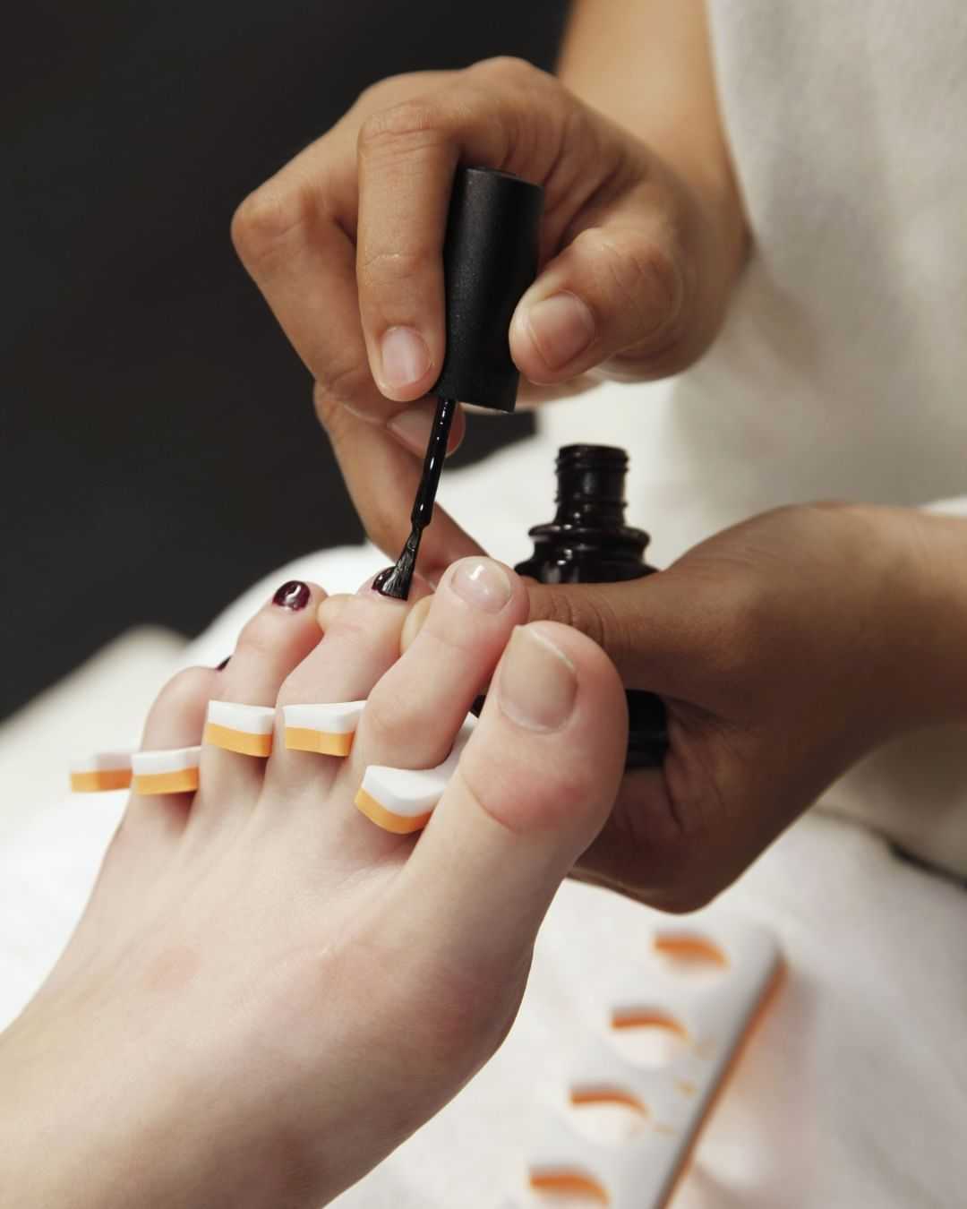Nail polish being applied to toenails during a pedicure session.